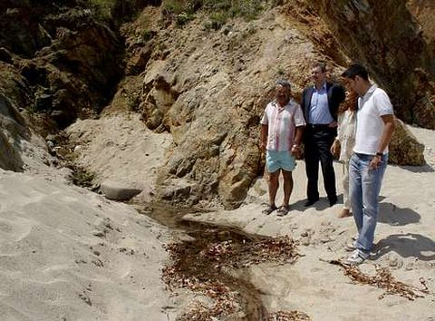 Miguel Ferreiro y Margarita Varela, en el centro, ante uno de los vertidos denunciados en la playa.