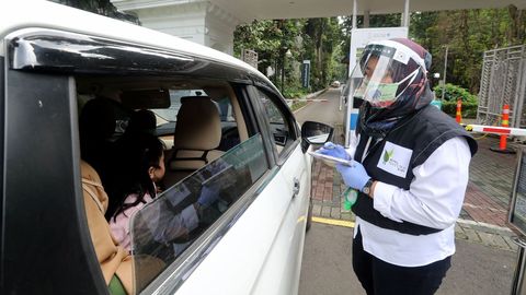 Un trabajador revisa la temperatura de los visitantes del jard�n bot�nico de Bogor, Indonesia, en su primer d�a de reapertura
