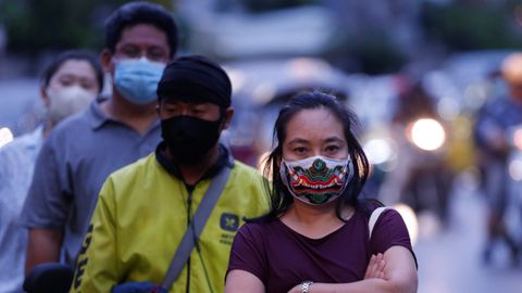 Ciudadanos hacen cola mientras esperan para coger alimentos en un puesto callejero durante en Bangkok