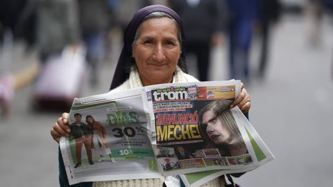 Una mujer sostiene una diario con la noticia de la dimisi�n de la presidenta interina en la primera p�gina