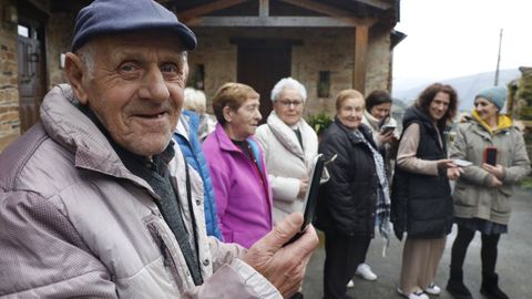 Un vecino levanta un teléfono en busca de cobertura en una de las calles del pueblo junto a otras residentes.