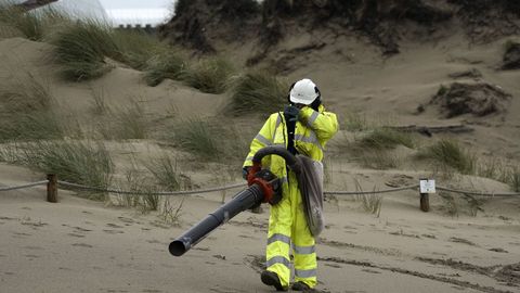 Operarios con aspiradores en la playa asturiana de Salinas