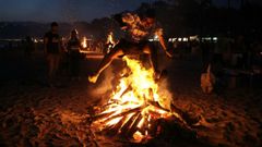 Un joven salta una luminaria en la playa de A Magdalena, en Cabanas, en foto de archivo.