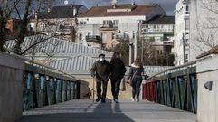 Dos personas con mascarilla cruzan hace unos d�as una de las pasarelas sobre el r� Cabe en Monforte