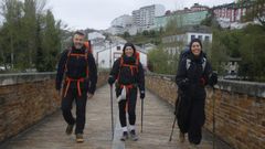 Tres peregrinos haciendo el Camino Primitivo a su paso por el puente romano de Lugo