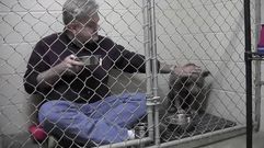El veterinario se toma el desayuno en la jaula con una perrita abandonada