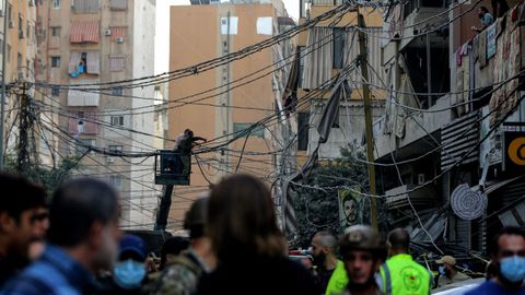 Operarios trabajan en la retirada de cables eléctricos destruidos por un ataque aéreo israelí que atacó un edificio en un suburbio del sur de Beirut.
