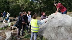 El fil�logo �lvaro Lorenzo (a la derecha) muestra la inscripci�n de la roca de O Preguntoiro a un grupo de vecinos de Pombeiro durante una reciente visita guiada al yacimiento medieval