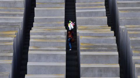 Un visitante lleva un globo con forma de unicornio a trav�s del monumento a las v�ctimas del Holocausto de Berl�n
