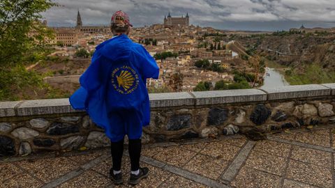 Una persona, ataviada con un chubasquero por la lluvia, observa la ciudad de Toledo desde el mirador del Valle.