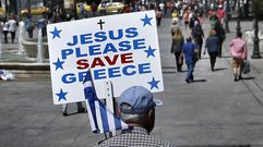 Un hombre pasea por la plaza de Syntagma de Atenas con un cartel que apela a la ayuda divina para Salvar a Grecia. 