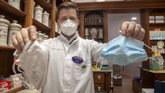 Antonio Busto, farmac�utico en Noia, muestra una mascarilla quir�rgica y otra FFP2