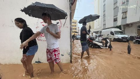 Varias personas caminan por las calles inundadas de la ciudad de Ibiza.
