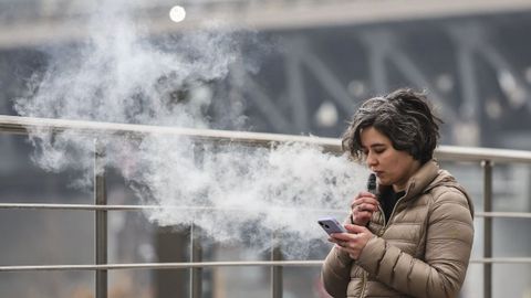 Imagen de archivo de una mujer con la nube de humo que sale al aspirar su vapeador