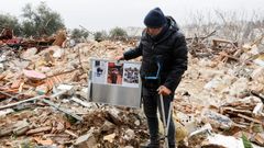 Un palestino sostiene fotos de la familia encontrados en los restos de la la casa demolida en el barrio Sheij Yarrah.