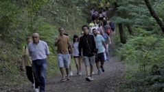 Personas caminando por la senda que lleva a Os Caneiros en una de las jiras