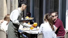 Un camarero atiende las terrazas de una cafeter&iacute;a en Santiago de Compostela.