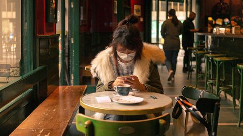 Una mujer toma un cafe en un bar del centro de Barcelona