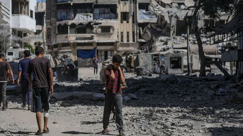 Civiles palestinos caminan por una zona destruida tras los ataques areos israeles en la ciudad de Gaza.