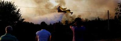 Varias personas observan la intervenci�n de un hidroavi�n en la extinci�n de un fuego declarado ayer en Pazos de Borb�n.