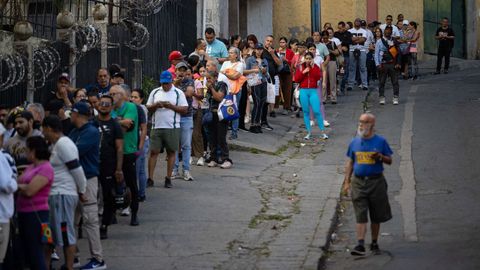 Personas hacen fila para ingresar en un supermercado este domingo, en Caracas (Venezuela)