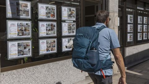 Una personas camina ante la vitrina de una agencia inmobiliaria en Santiago de Compostela.