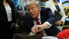 El presidente de Estados Unidos, Donald Trump, recoge una moneda de desaf�o para entregarla a los veteranos durante un evento de firma de �rdenes ejecutivas en el despacho oval de la Casa Blanca en Washington.