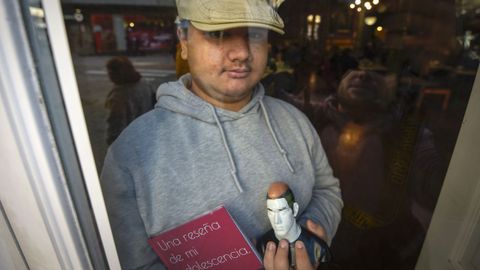 Lucas Oubi�a Fojo, con su libro y una figura, tras una cristalera del Caf� Moderno, en Pontevedra