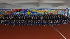 Foto de familia del alumnado de infantil y primaria delante de un mural que conmemora el centenario