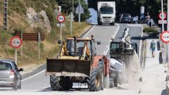 Operarios limpiando esta semana la carretera por la arena de A Cruz, y coches esquivando.