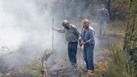 Vecinos de Pentes colaboran para que el fuego no cruce el camino que les separa de sus casas.