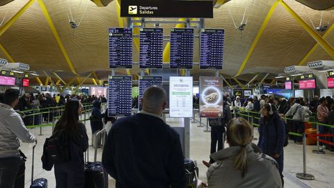 Pasajeros consultando el estado de sus vuelos en un aeropuerto.
