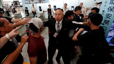 Un miembro del aeropuerto de Hong Kong intenta contener a los manifestantes ante el mostrador de una compa��a a�rea 