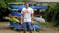 Nico Adega, expaciente de osteosarcoma, frente a varias piraguas en el club fluvial de Lugo. 