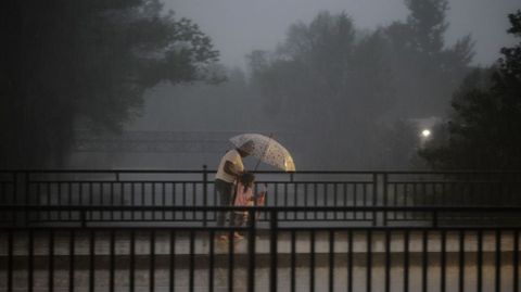 Una mujer y una ni�a tratan de taparse con un paraguas.