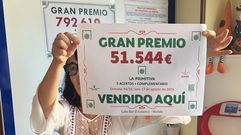 Merchi L&oacute;pez, del cafe-bar El Estanco de Melide, sostiene el cartel que acredita el reparto de un boleto premiado con 51.544 euros