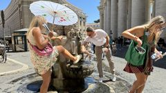 Unos turistas se refrescan en una de las fuentes de la plaza de San Pedro, en El Vaticano