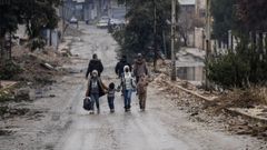 Una madre y sus hijos de camino a su casa en Alepo, este domingo