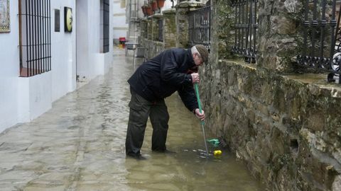 Un hombre achicando el agua cerca de las casas en Grazalema, en C�diz