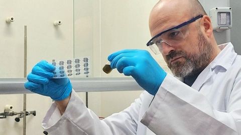 Juan Ignacio Paredes en el laboratorio del Grupo de Materiales Carbonosos, sosteniendo un frasco que contiene una tinta de material bidimensional y un sustrato flexible transparente sobre el que se han impreso microelectrodos del material bidimensional.