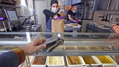 Un cliente pagando con el m�vil en un establecimiento de comida preparada.