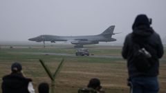 Curiosos observan desde el exterior el bombardero estadounidense que aterriz� ayer en la base de Fairford de Reino Unido. 