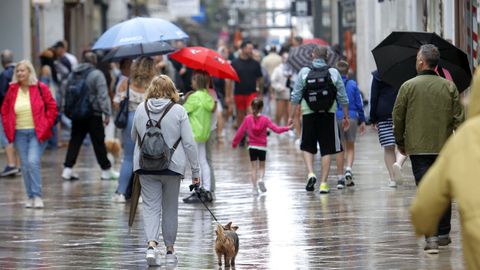 Varias personas caminando por una calle comercial gallega