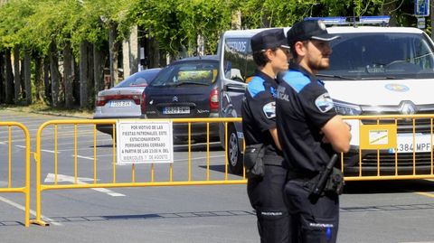 Dos agentes de la Policía Local frente a las vallas que cerraban durante las fietas del año pasado el paso al estacionamiento del Parque dos Condes