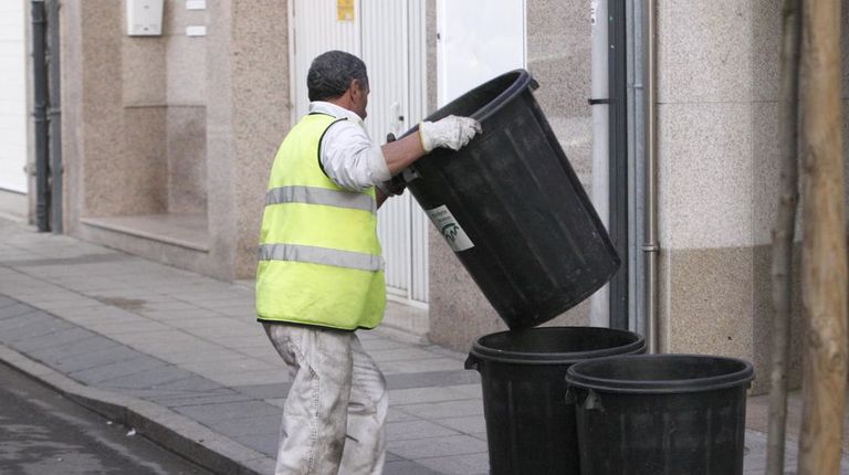Un trabajador de FCC en Monforte pone los cubos de basura en una calle de Monforte