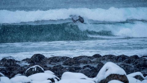 Una surfera toma una ola en plena nevada en la costa de Noruega