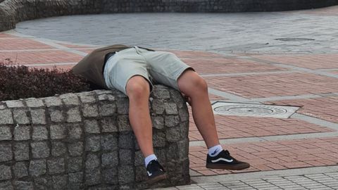 Hombre dormido en el paseo de la playa de Poniente, en Gij�n