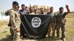 Combatientes iraqu�es posan con una bandera de Estado Isl�mico tras reconquistar Al-Shahabi