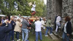 Los devotos pasan bajo la figura de San Miguel, una de las tradiciones de la romera de Breamo.