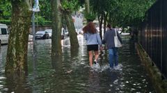 J�venes caminando en una calle anegada.